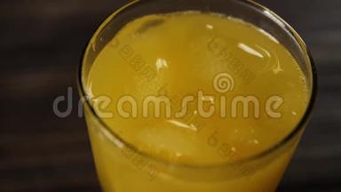 顶部的<strong>冰块</strong>旋转和<strong>漂浮</strong>在新鲜橙汁在一个高大的玻璃木桌上